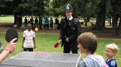 laughing policeman playing table tennis with some kids